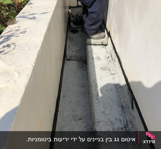 אדם יושב ליד קיר עם איטום שחור על הרצפה